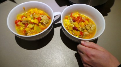Two steaming bowls of vegetable and meatball soup
